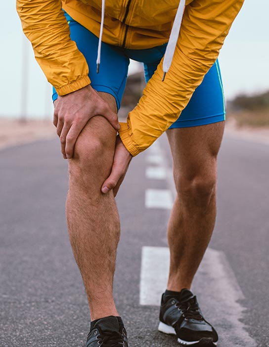 man on road holding knee